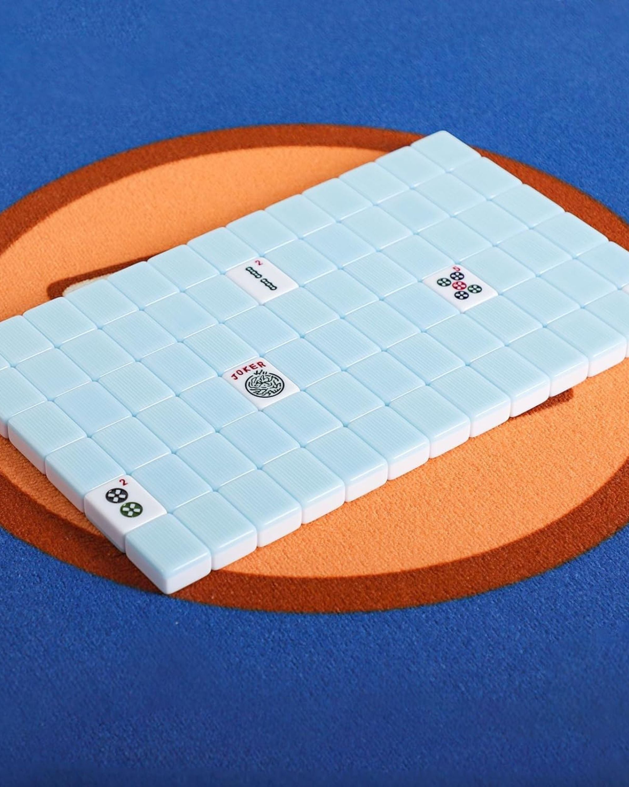 Folded mahjong mat with light blue tiles on top, printed suit faces visible