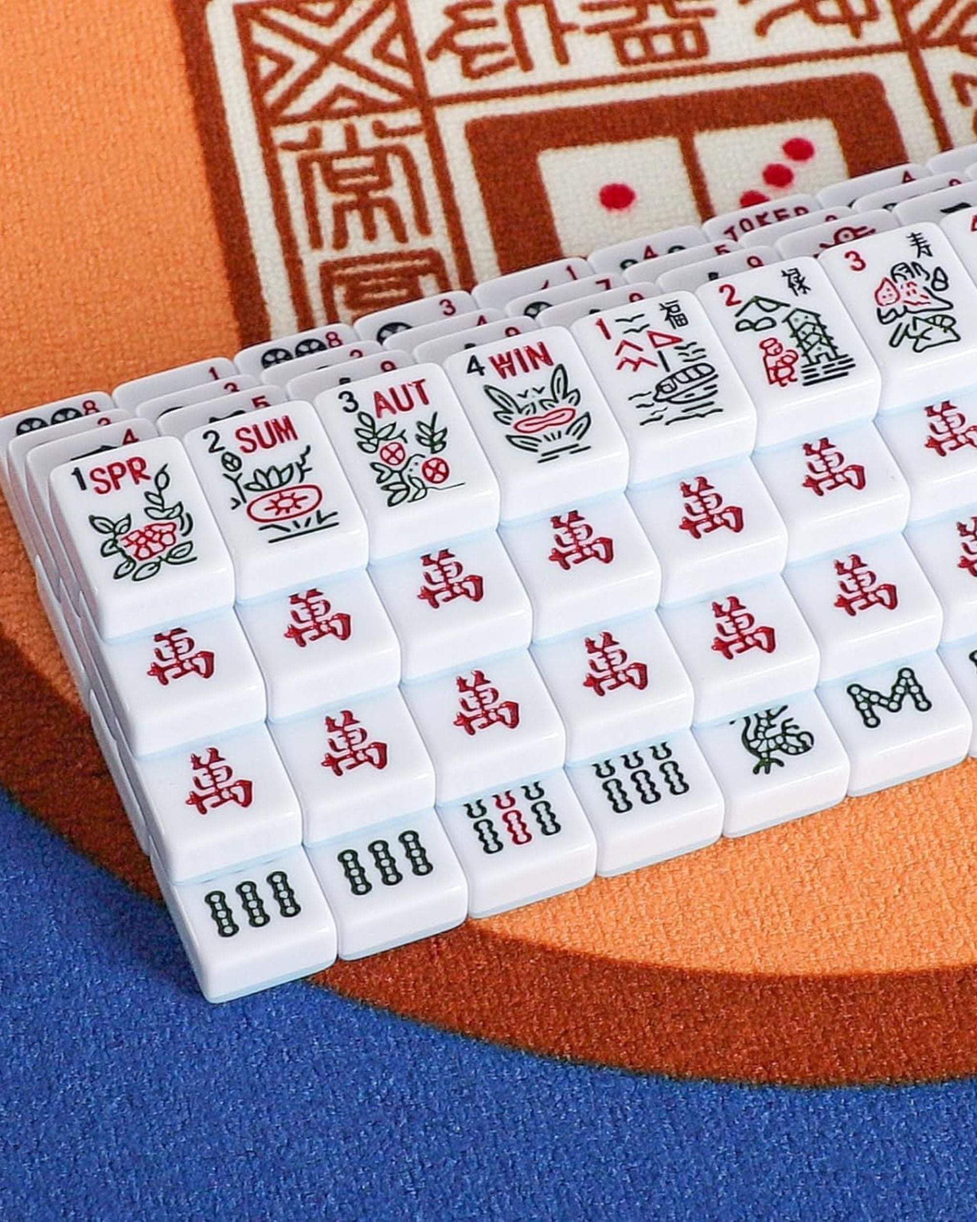 Close-up of white mahjong tiles with red and black symbols on a mat