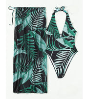 Printed halter one-piece swimsuit with high-cut legs and sheer cover-up skirt, tropical leaf print