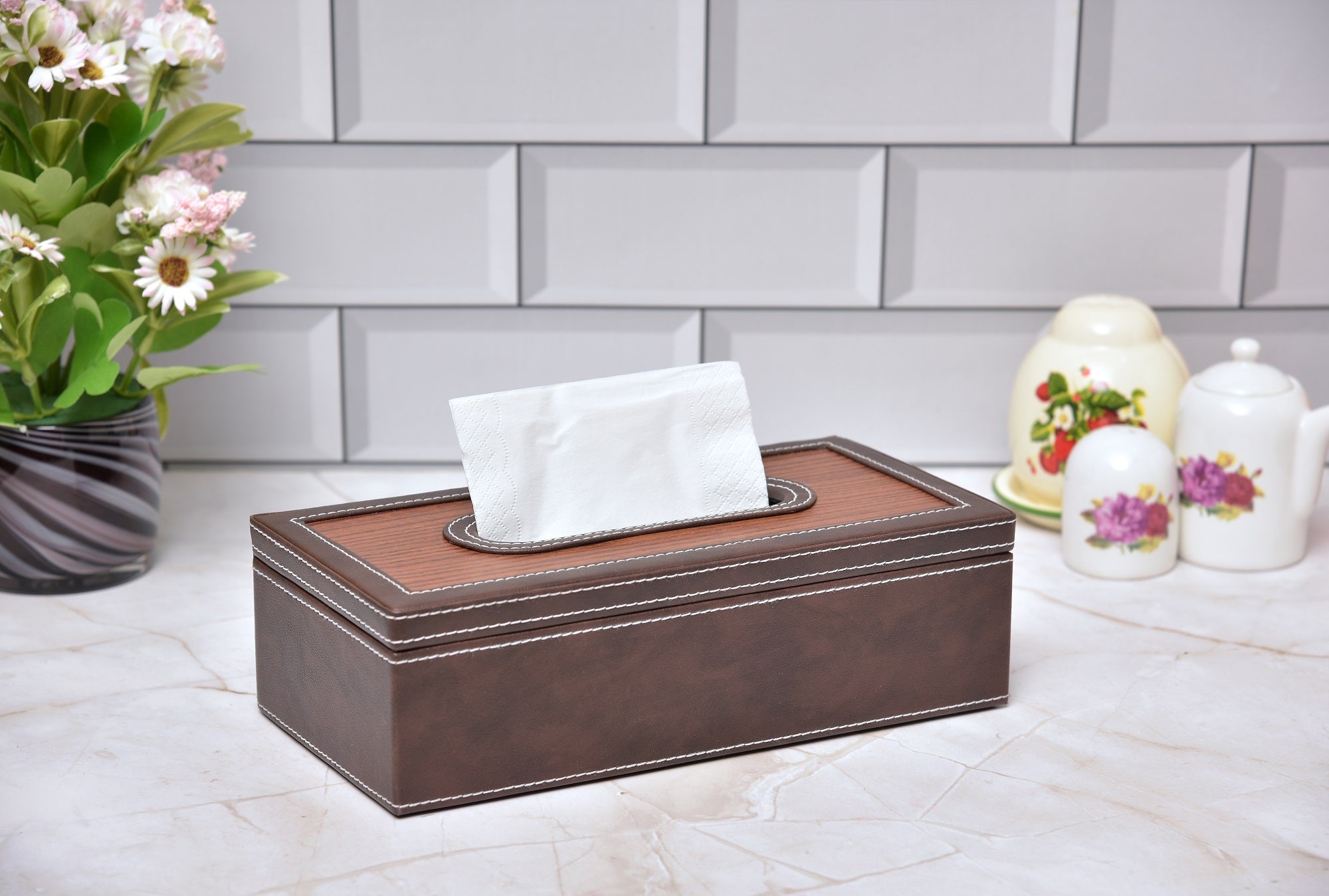 Rectangular tissue box holder with dark brown leatherette body and wooden-look top, tissue visible