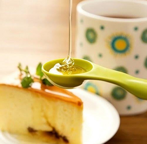 Rainbow measuring spoon pouring into a small dish, green bowl with measurement marks