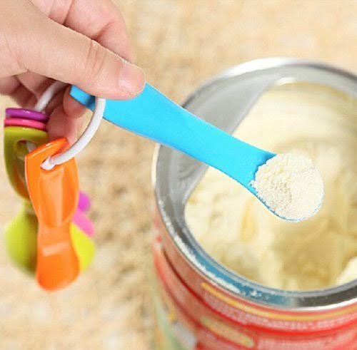 Blue measuring spoon held above a jar with white powder, measurement marks on handle