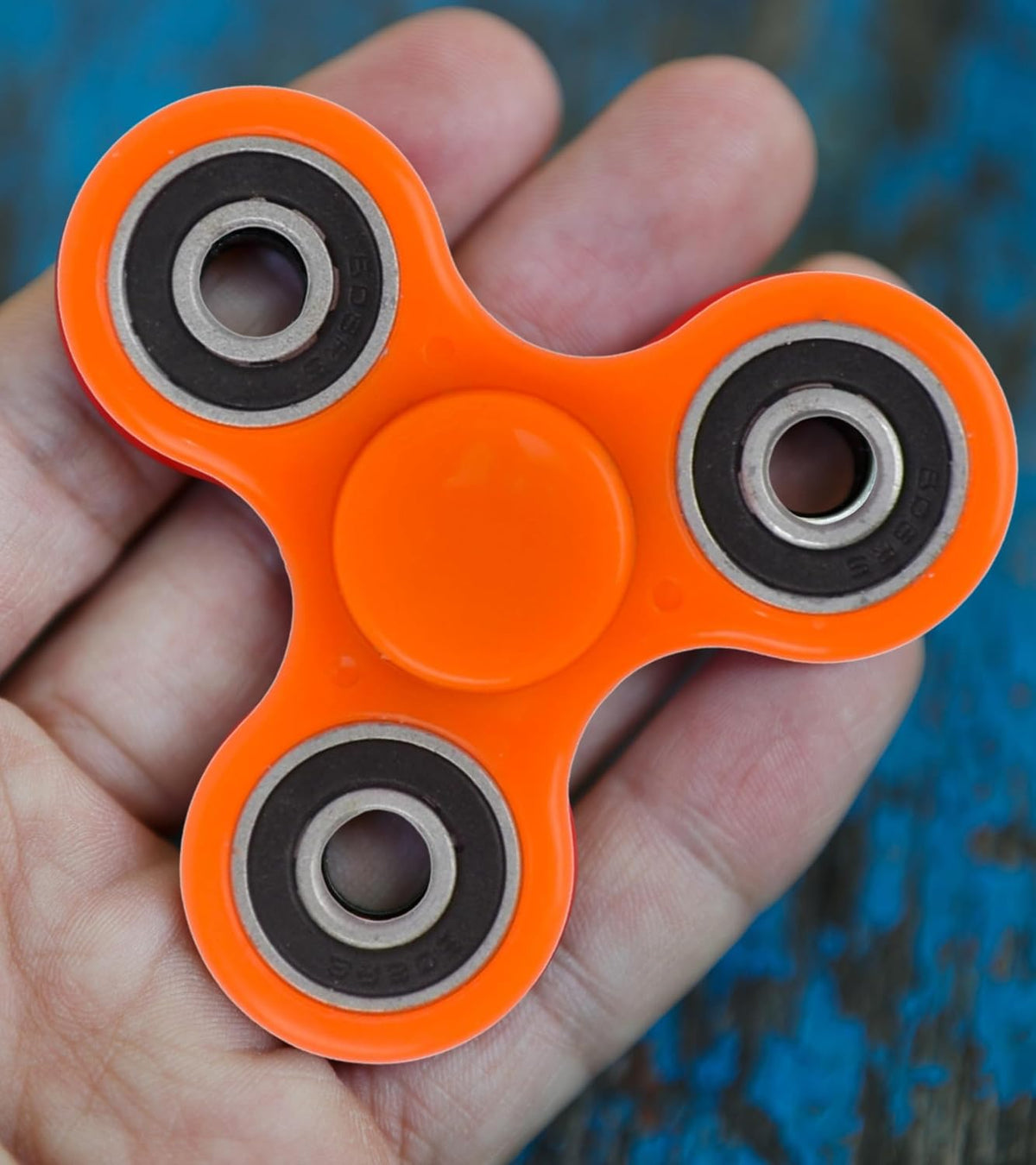 Orange four-bearing hand spinner fidget toy close-up showing bearing wheels