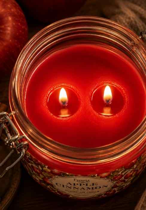 Double-wick candle with red wax, shown through clear glass jar opening