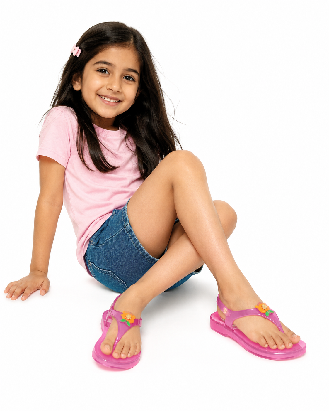 Bright pink girls' jelly sandals with floral charms, worn by a child