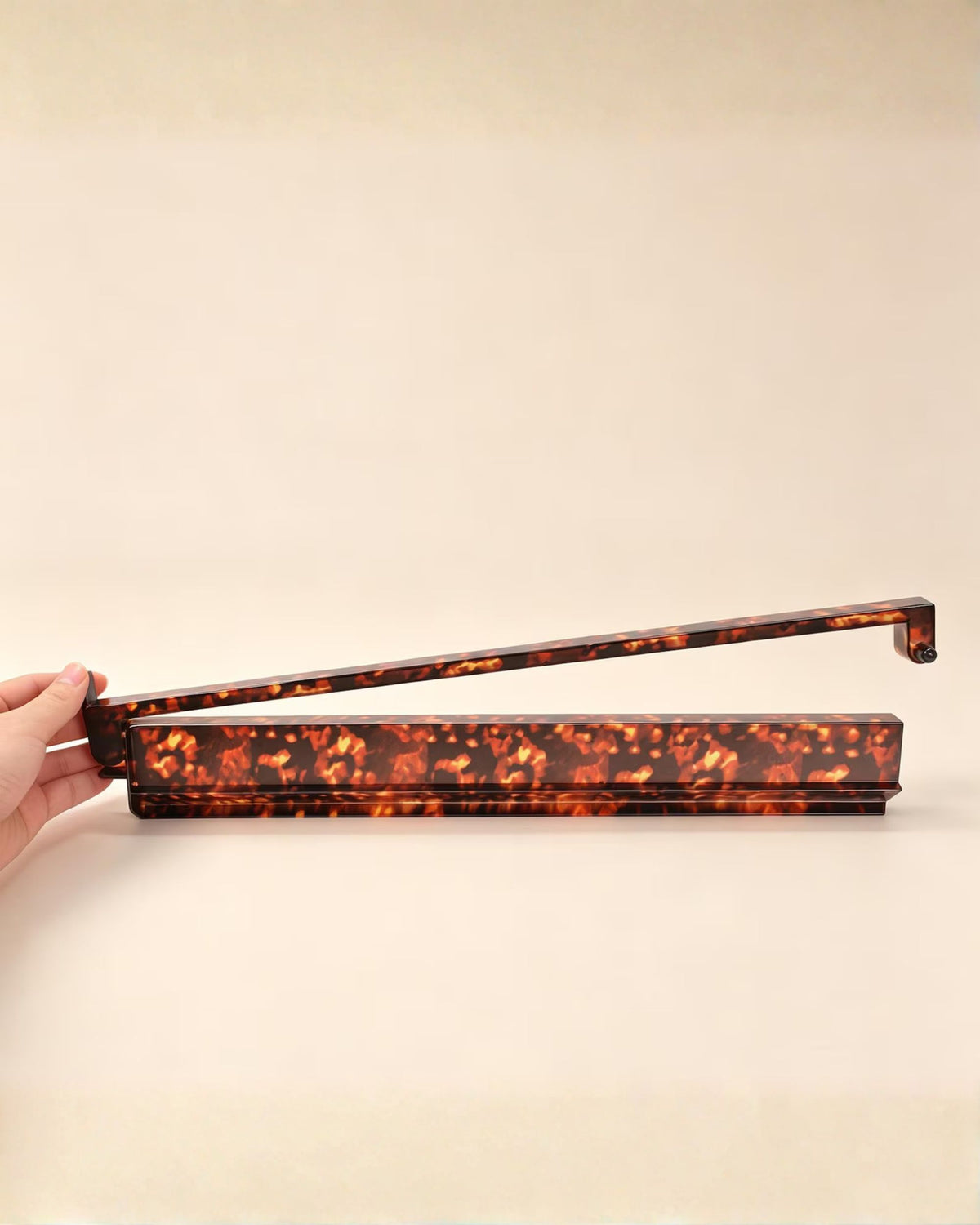 Tortoise shell ABS mahjong tile rack held by hand, end support visible
