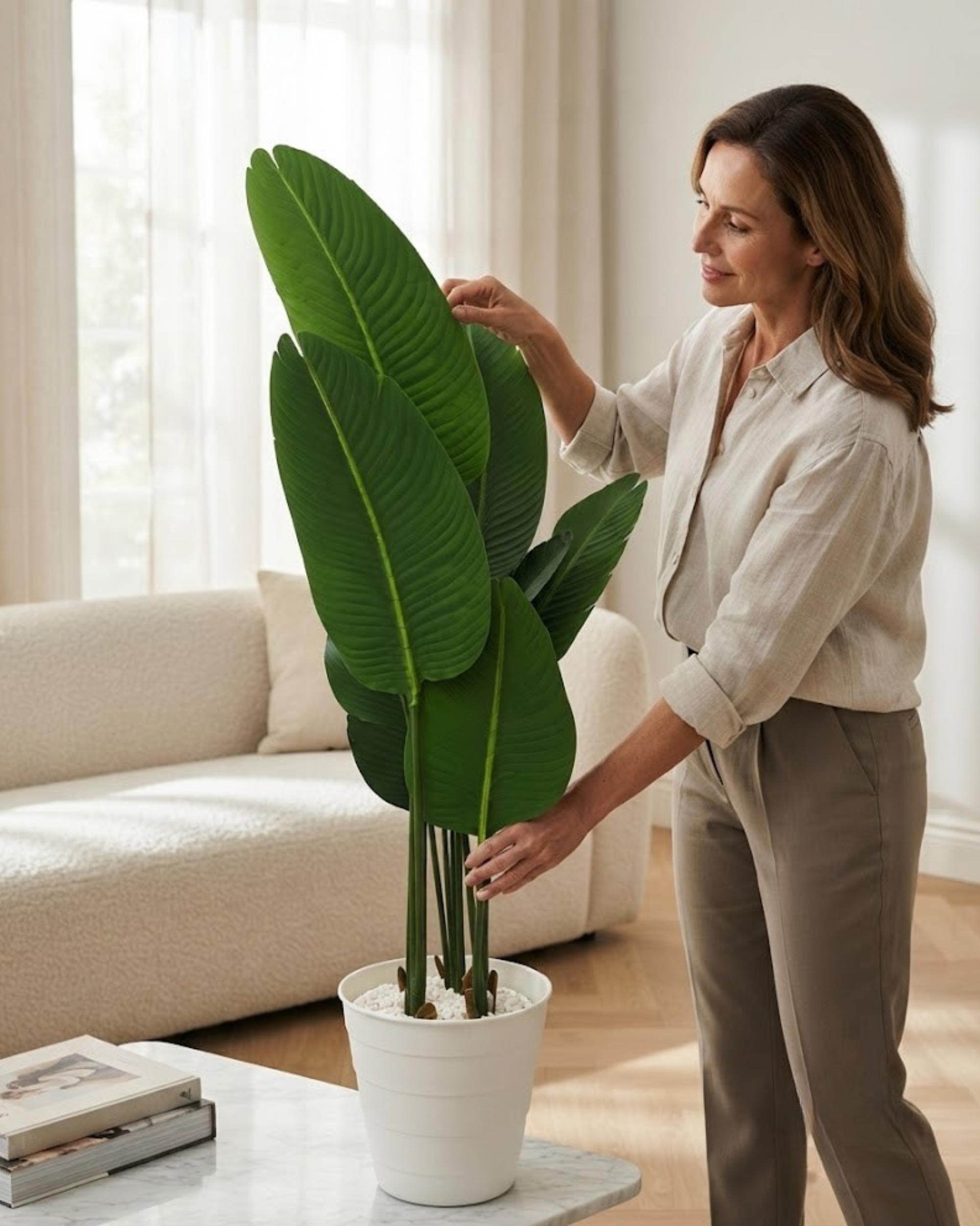 Artificial big-leaf plant in white pot, broad green leaves on tall stems