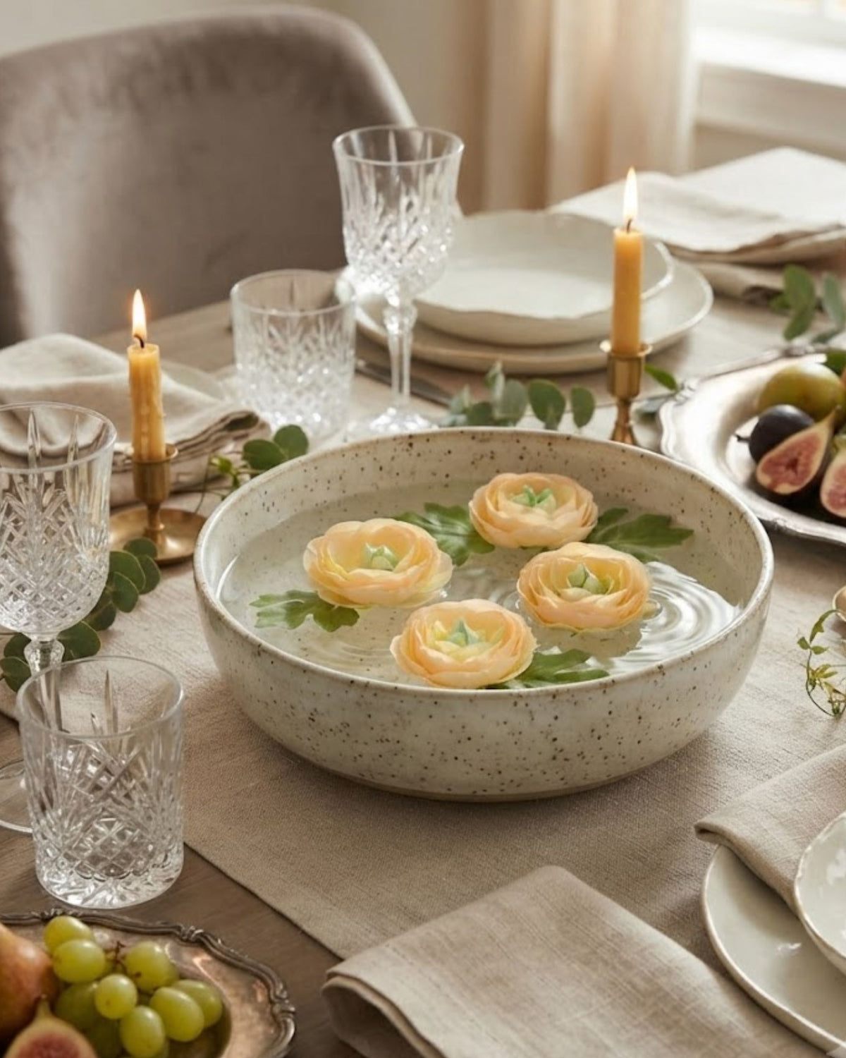 Blush-cream artificial ranunculus flowers floating in a bowl with green leaves