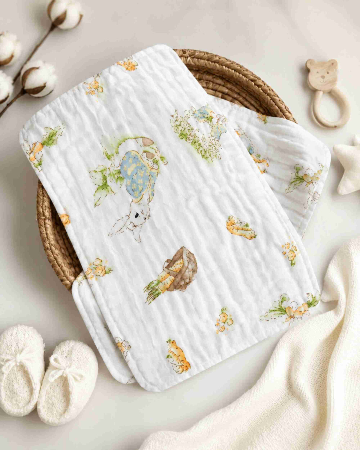 White baby burp cloth folded on bedding, quilted texture with bunny and carrot garden print