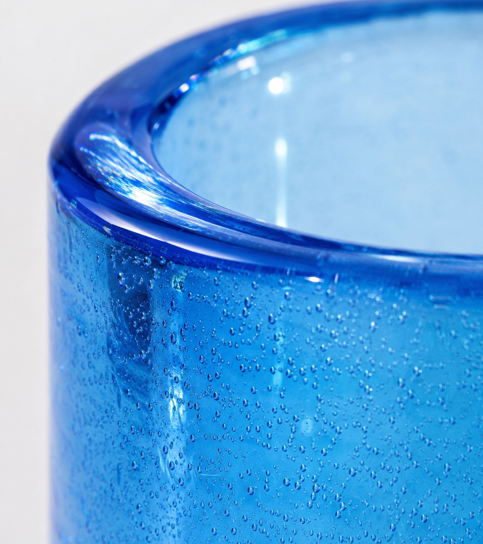 Close-up of blue textured glass votive holder rim and wall detail