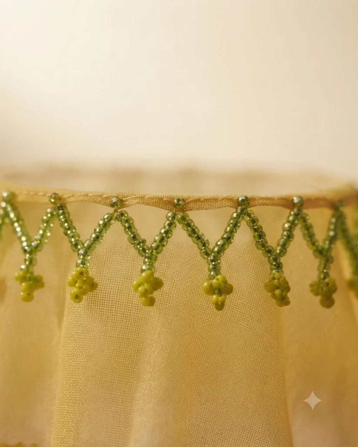 Green mesh drink glass cover detail with hanging pom-pom bead trim