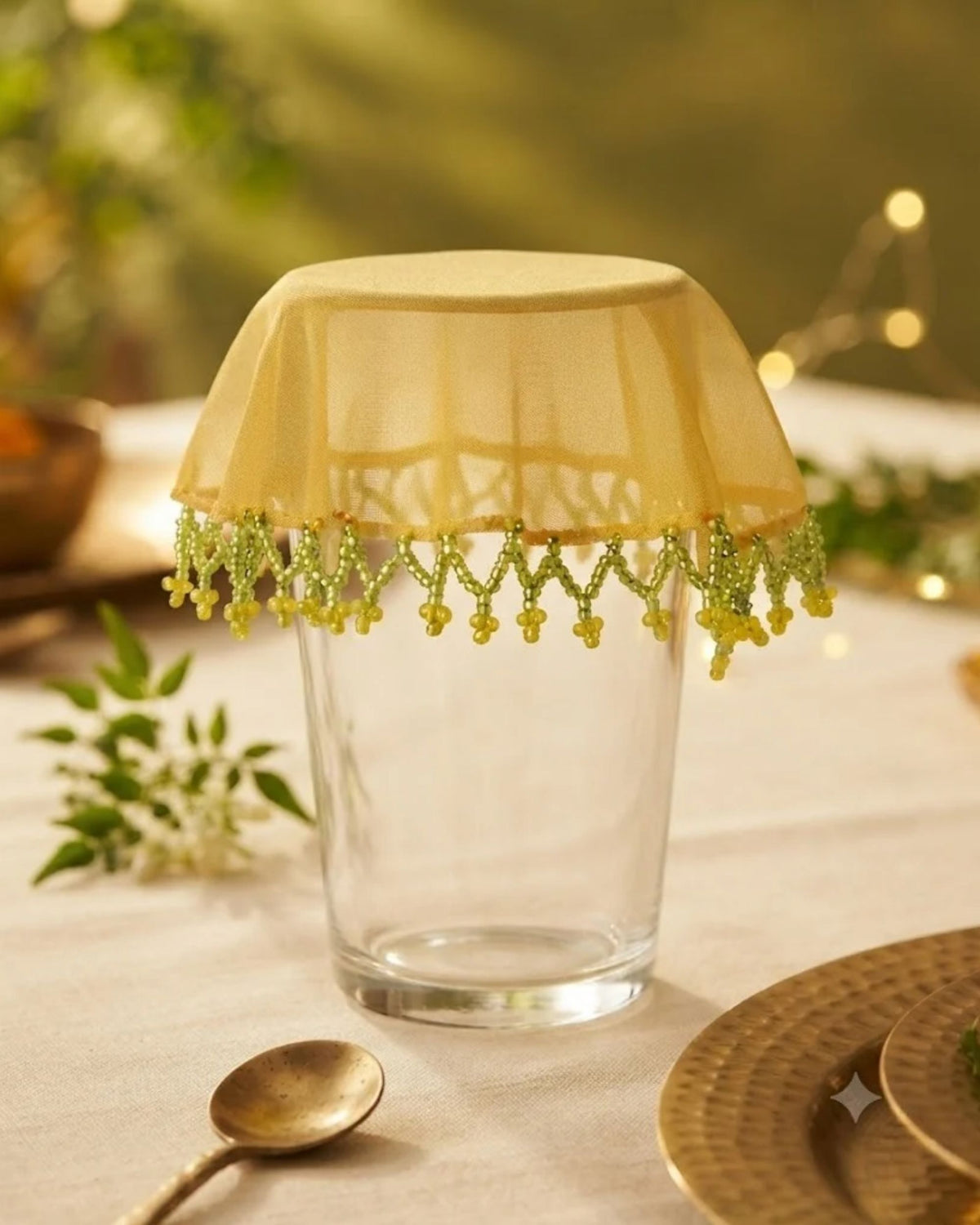 Yellow mesh drink glass cover with green beaded fringe fitted to a glass