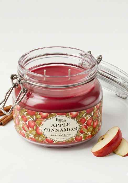Apple cinnamon scented candle in clear glass jar with red wax and two wicks