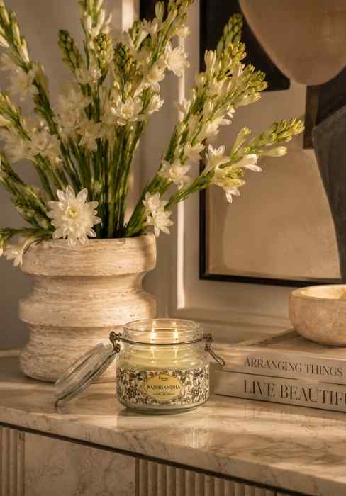 Small glass jar candle with green wax and lid, on a tabletop