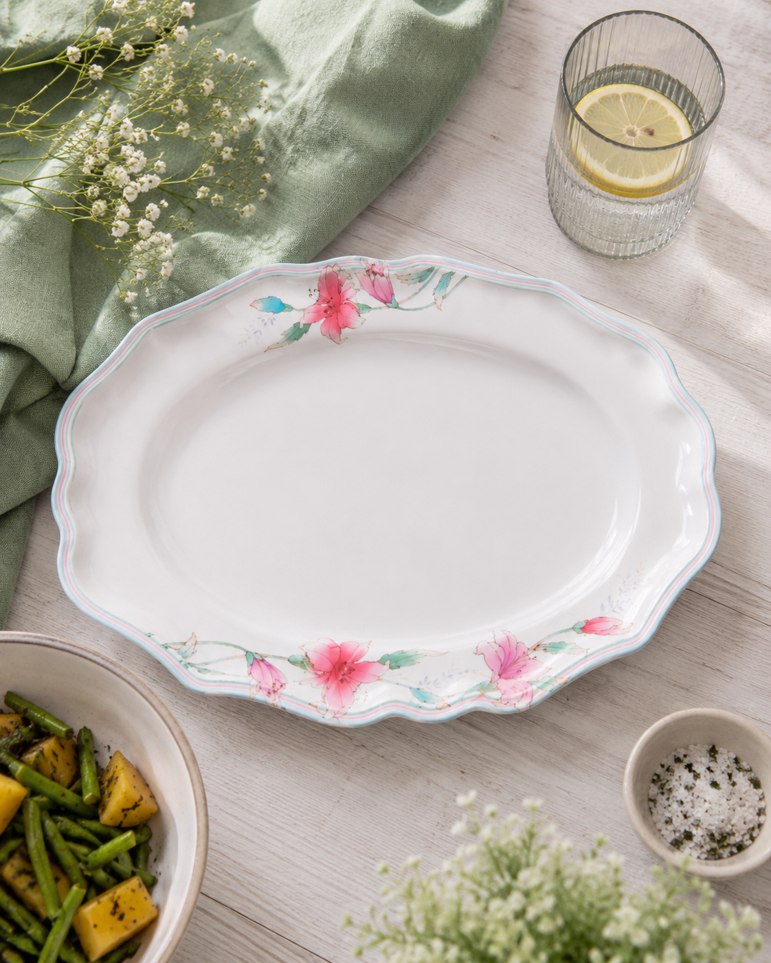 White oval melamine plate with pink lily blossoms and blue-green leaf border around rim.