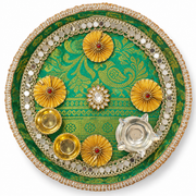 Round festive pooja thali with green patterned base, gold floral accents, and silver diya-like holders