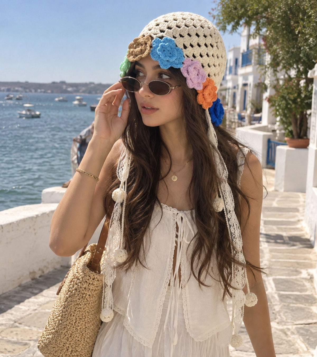 Beige crochet cap on model with colorful flower appliques and long tassel ties