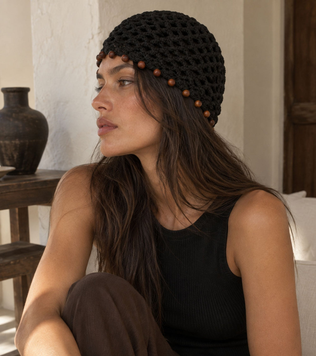 Black crochet beanie with brown beaded trim, shown in side profile