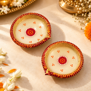 Round decorative wax diyas with yellow-gold rims and red dot patterns, pair