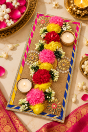 Festive pooja tray with colorful flower garlands and two tealight holders