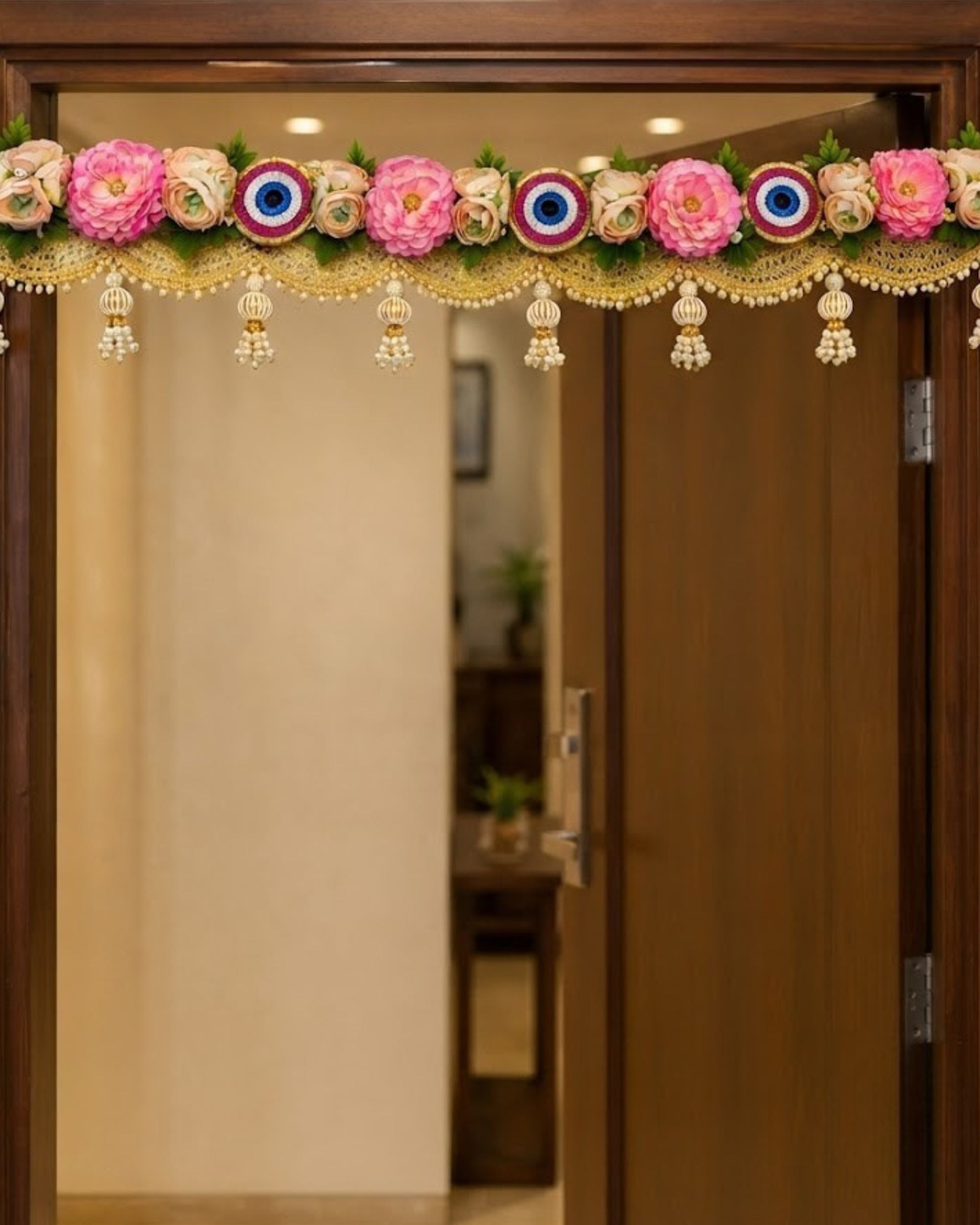 Floral toran door hanging with pink flowers, evil-eye motifs, and hanging bead tassels