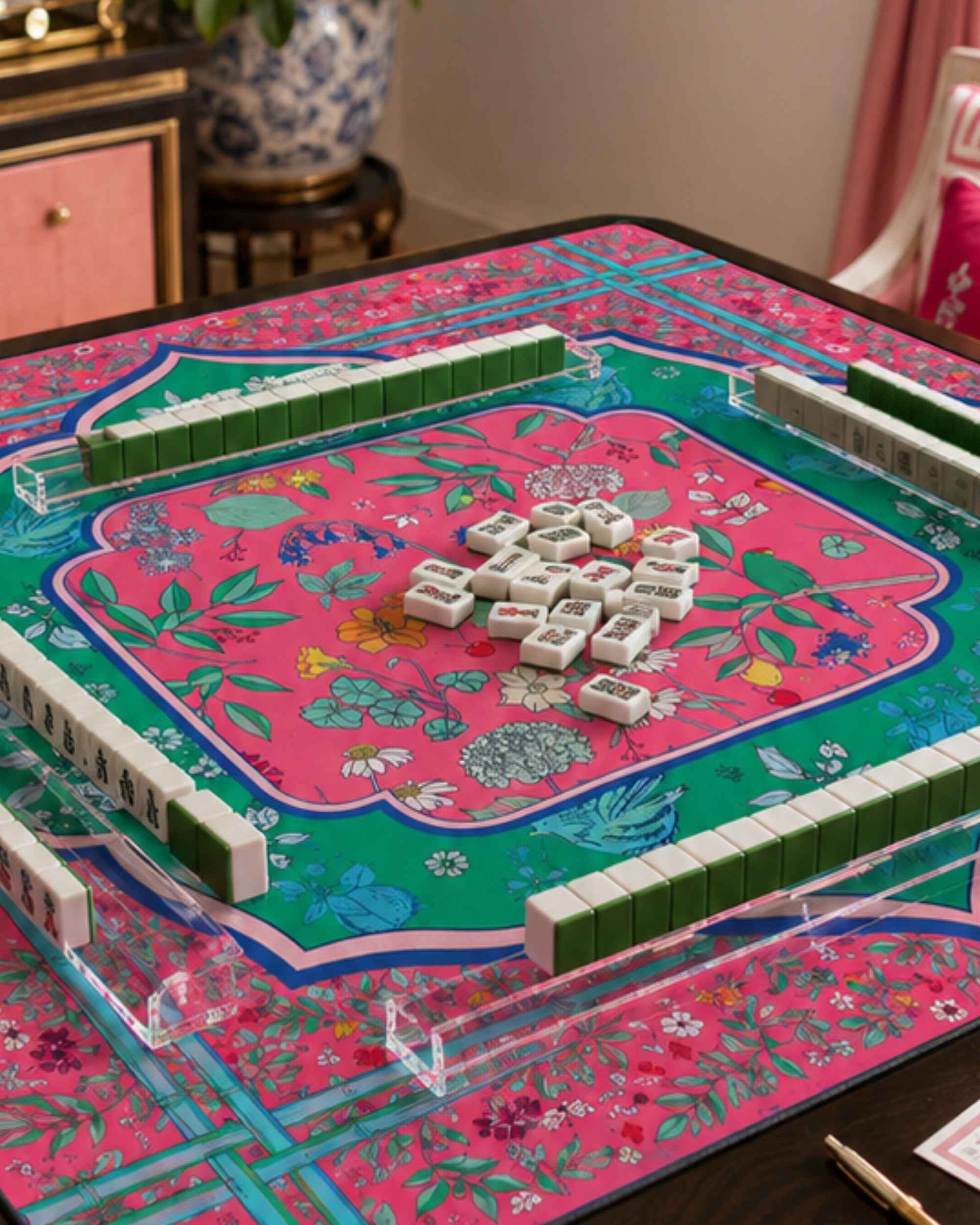 Floral mahjong table mat with pink center and green border, surrounded by tiled racks