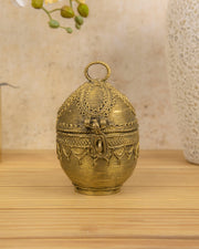 Brass decorative storage container, egg-shaped with ring handle and tribal engravings.