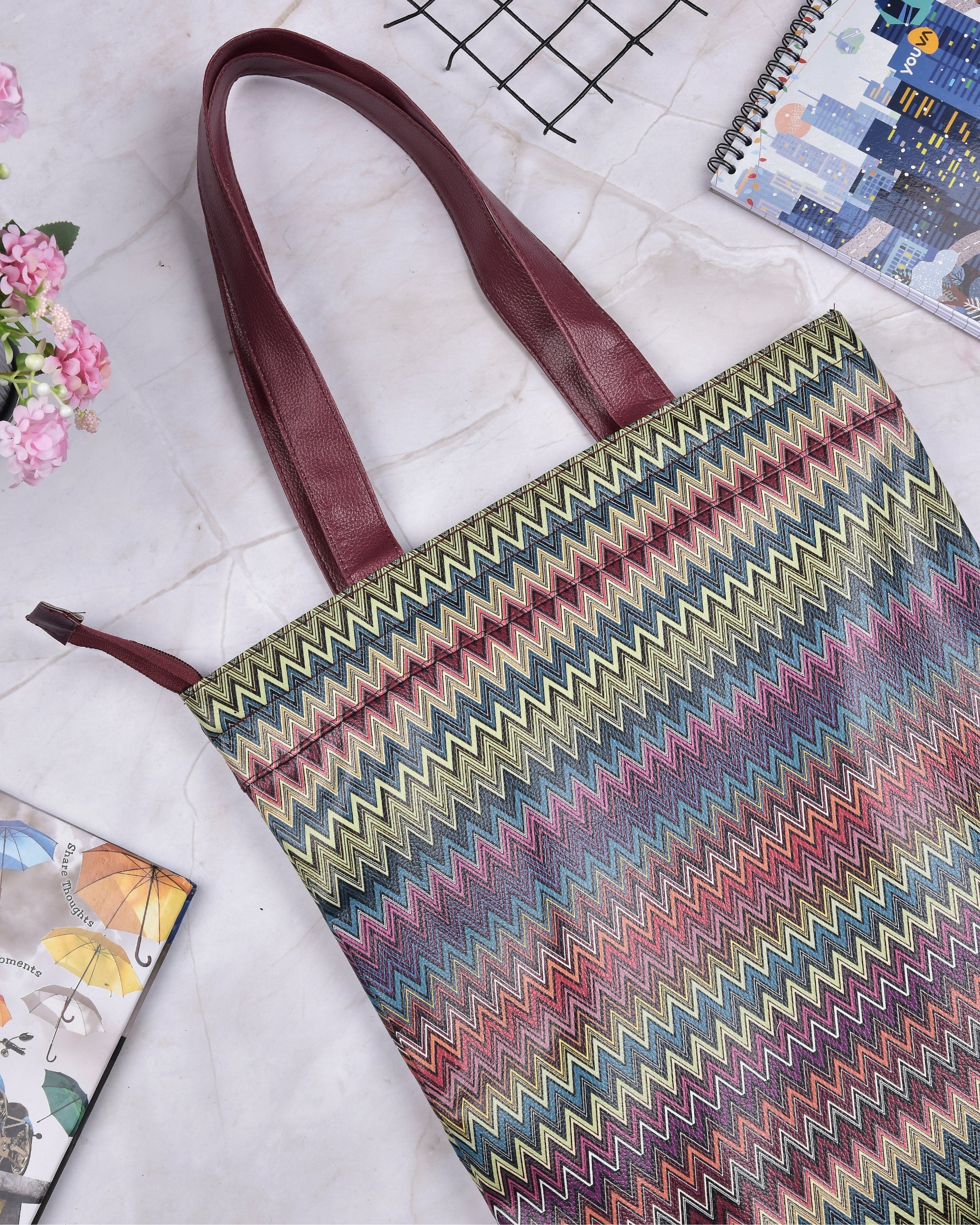 Zigzag print tote bag with maroon shoulder handles and multicolor chevron pattern