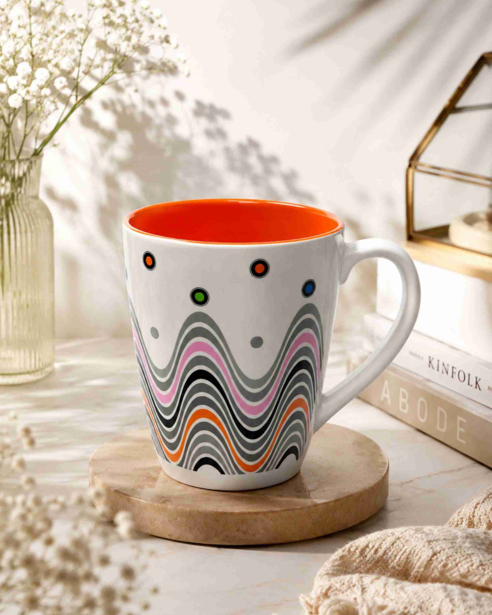 Ceramic coffee mug with orange interior, white body, and colorful wave pattern