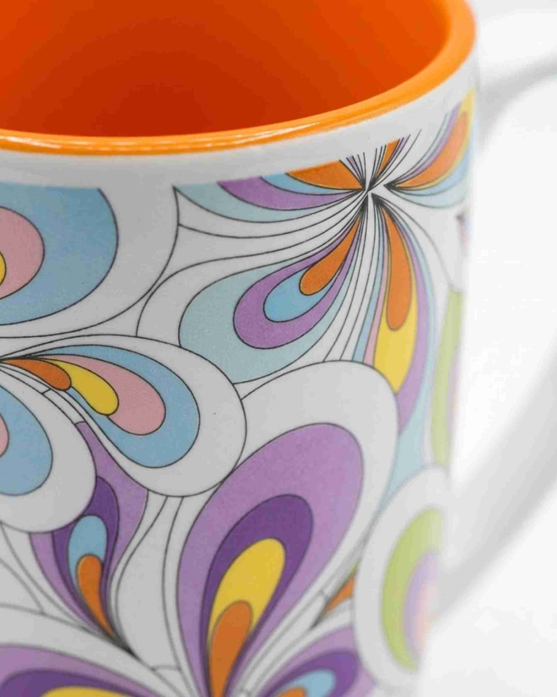 Ceramic mug side with colorful swirling floral design and orange interior rim