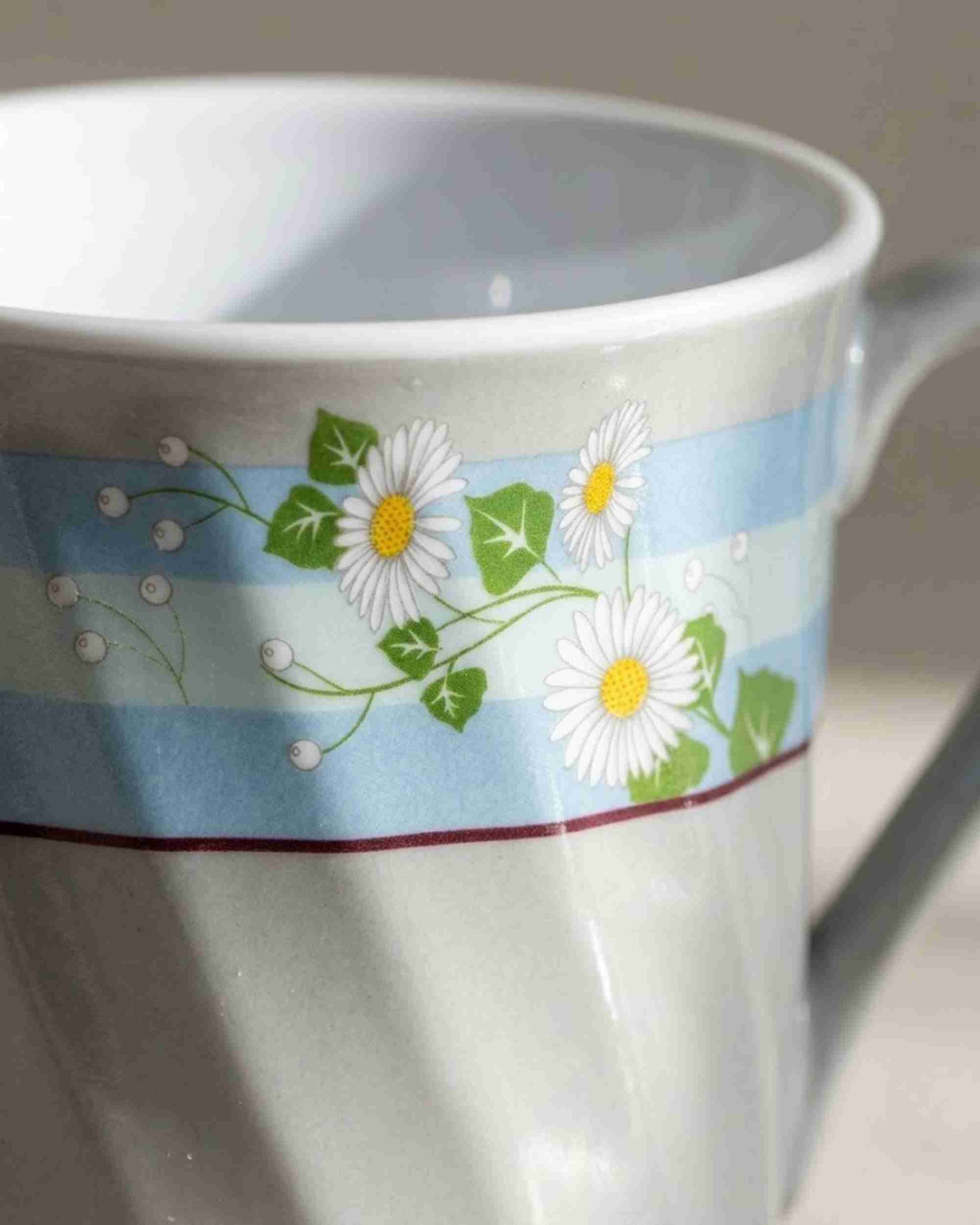 Close-up ceramic mug with blue floral band and white daisy flowers