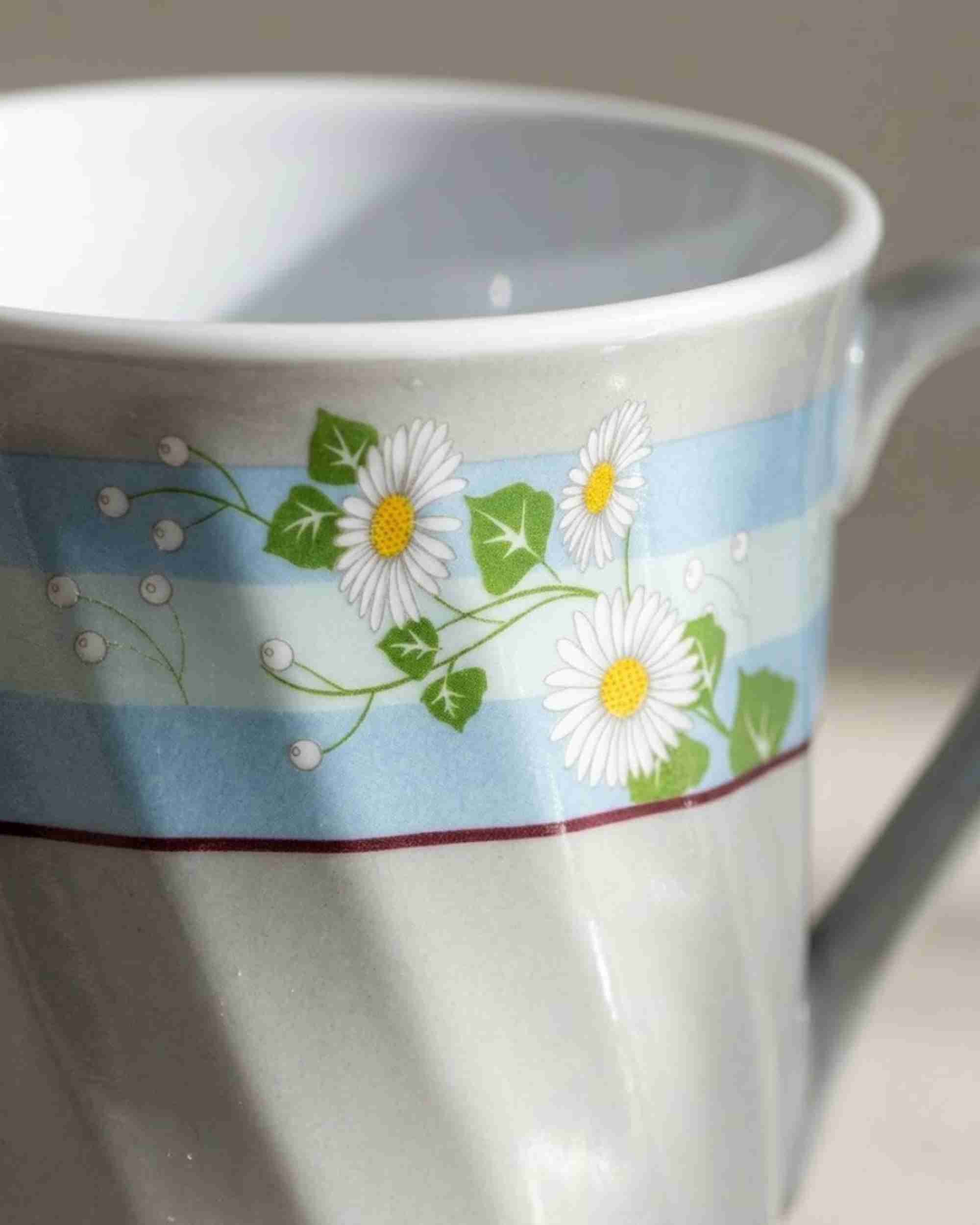 Close-up ceramic mug with blue floral band and white daisy flowers