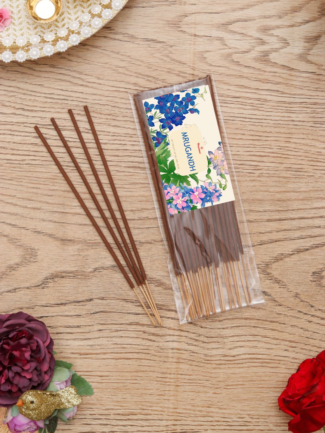 Incense stick pack with floral label and several brown sticks laid on wood surface