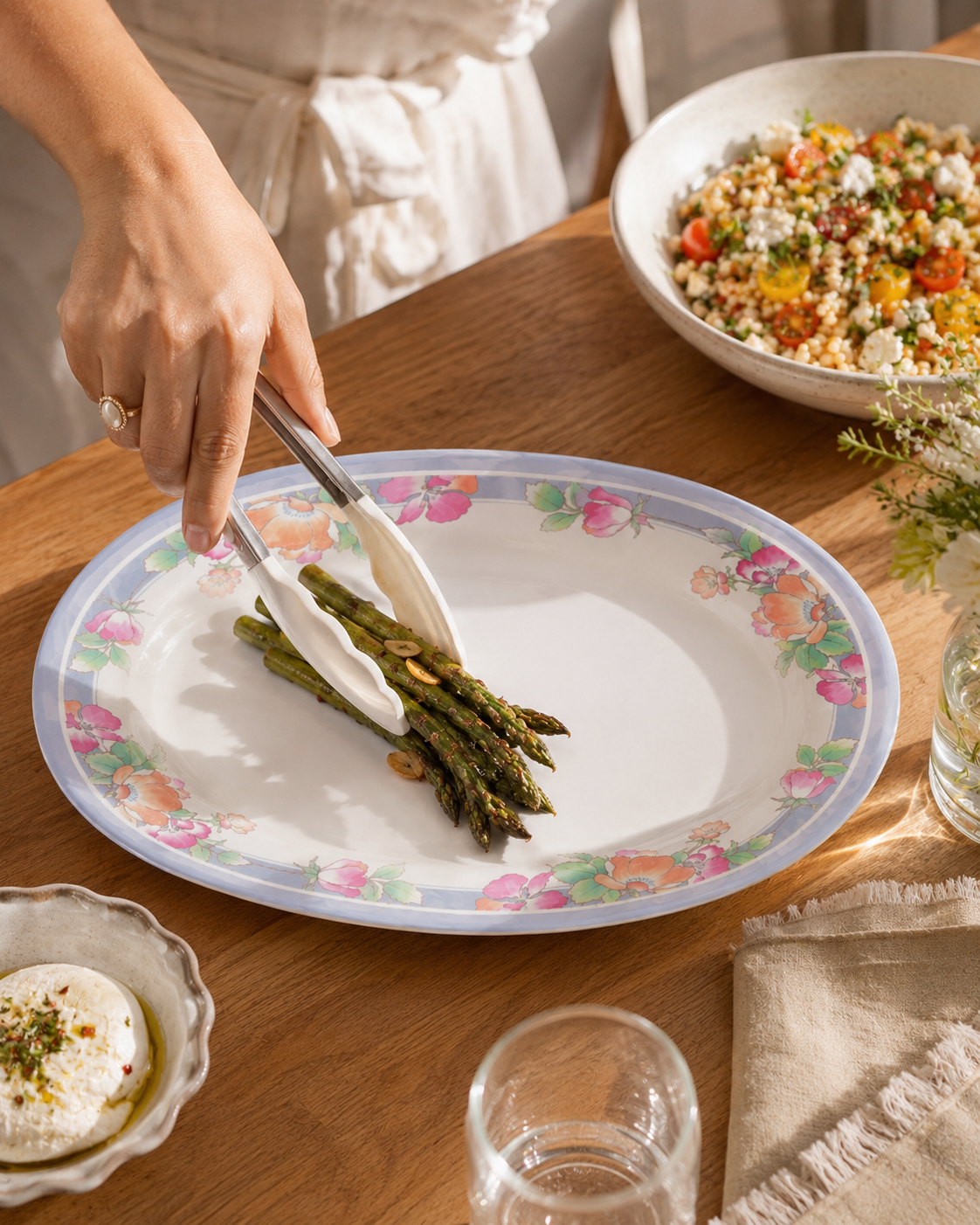 Oval floral serving plate holding green asparagus with a fork