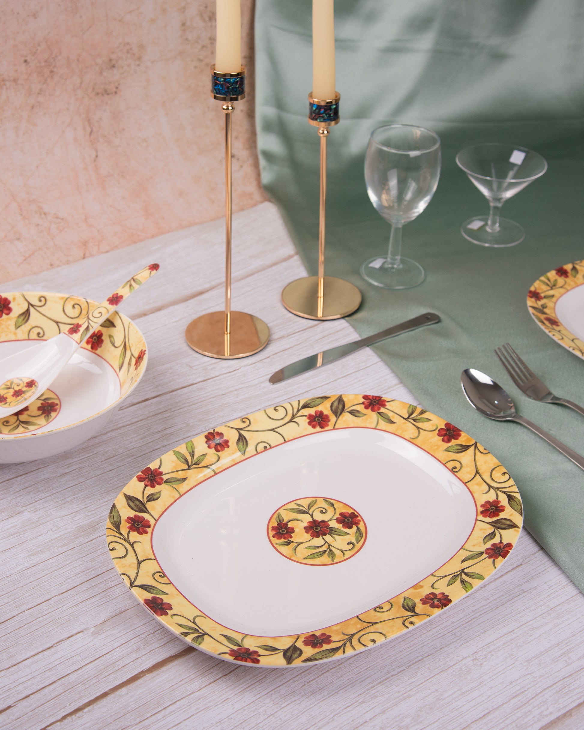 Decorative plate with floral design on a table setting with cutlery and glasses.