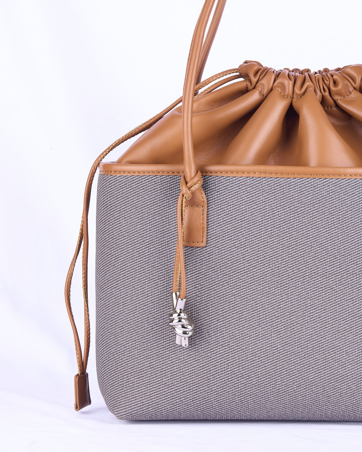 Beige woven women's handbag with tan leather trim, ruched drawstring top, key charm