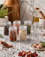 Clear glass airtight storage jars with clip-lock lids, filled with assorted spices