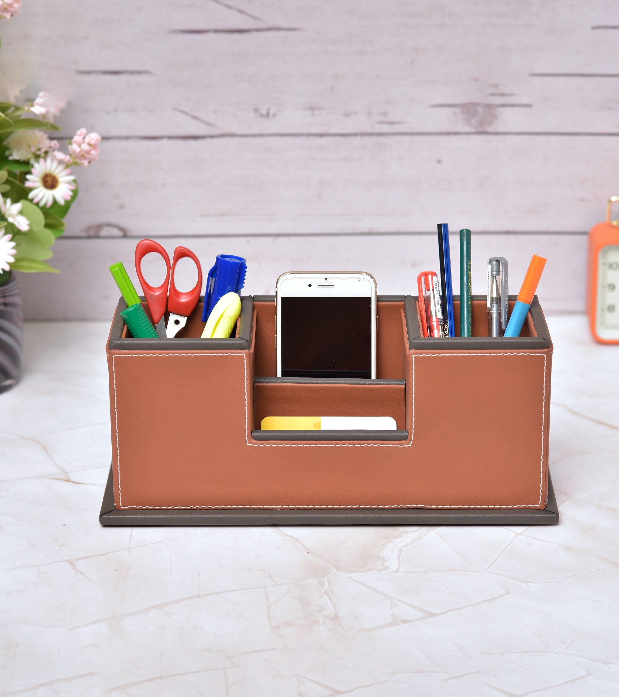Two-compartment desk organizer holding stationery and phone, orange and tan faux leather look