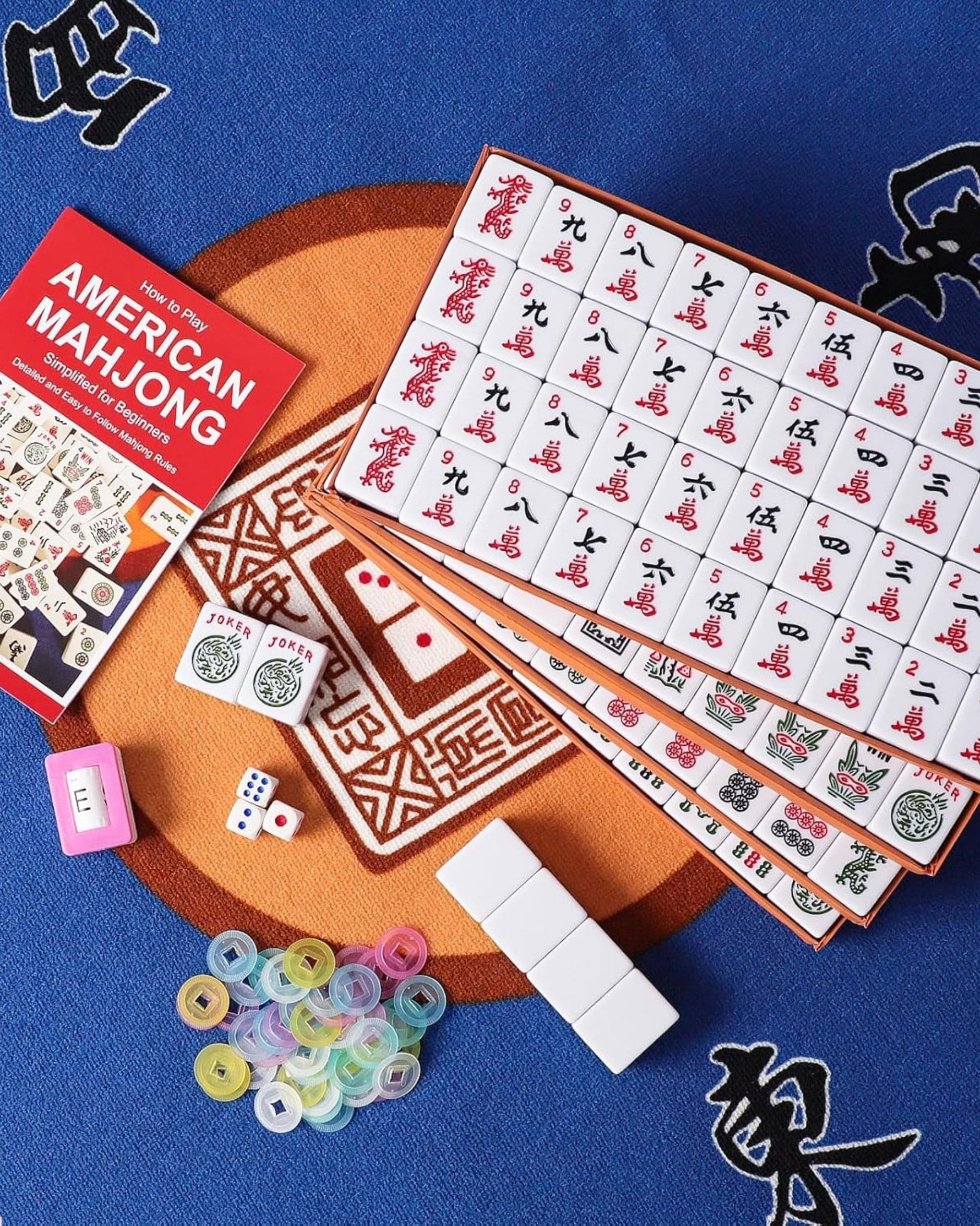 Mahjong tiles with dice, chips, and instruction booklet on blue fabric