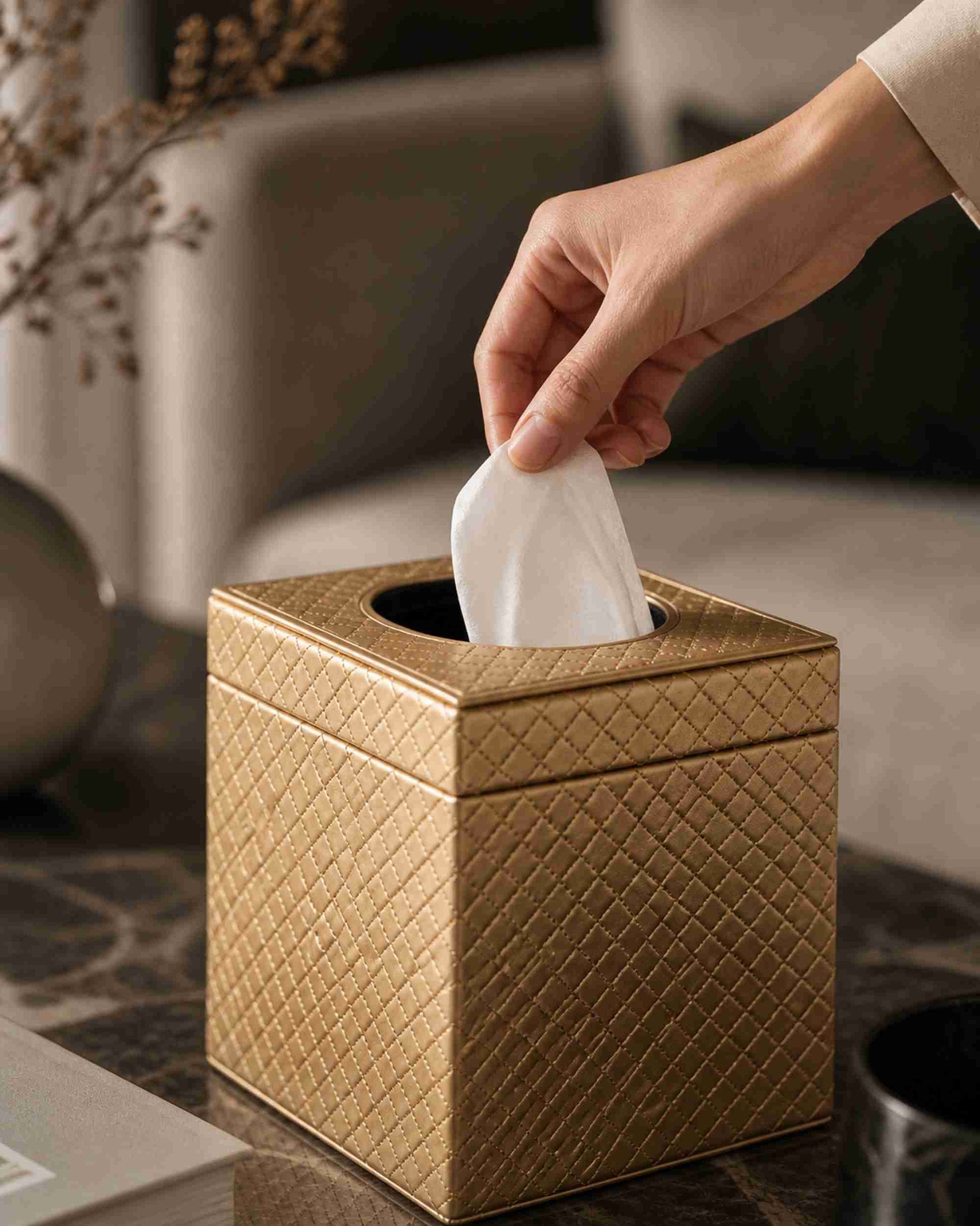Metallic leatherette tissue box holder in light tan textured finish with tissues pulled by hand