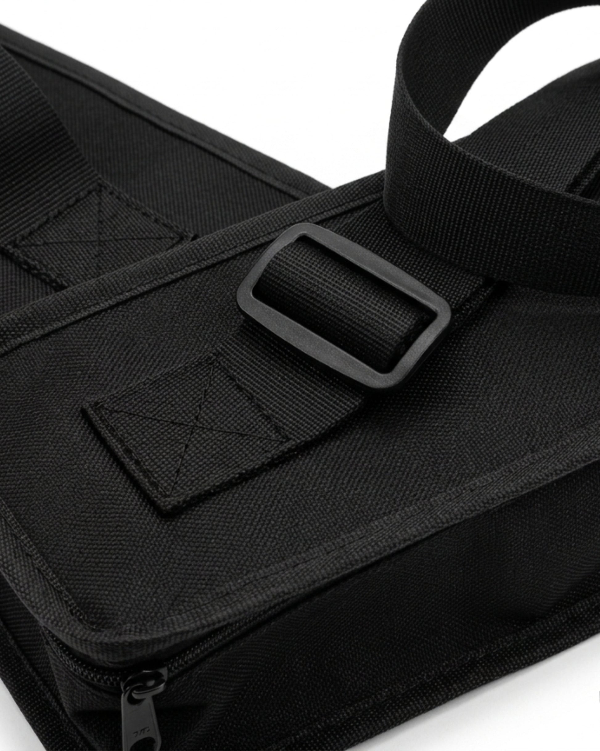 Black carry bag close-up with webbing strap, rectangular buckle, and stitched pocket