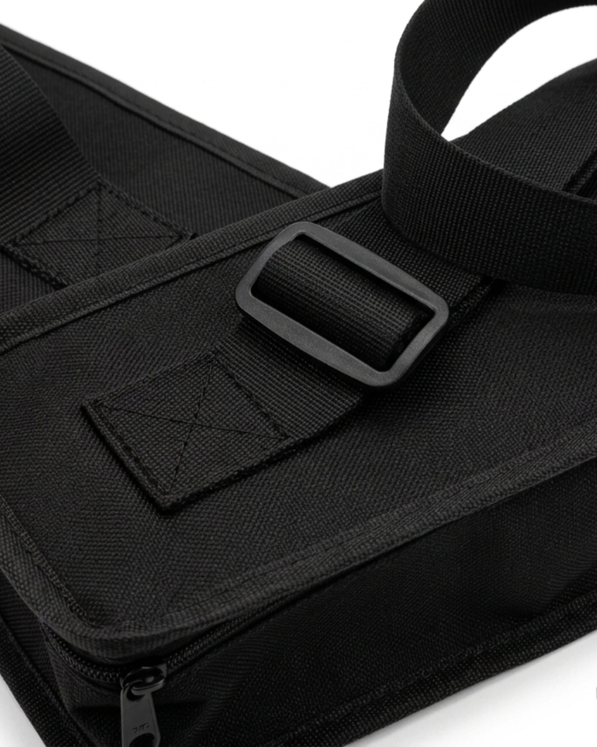 Black carry bag close-up with webbing strap, rectangular buckle, and stitched pocket