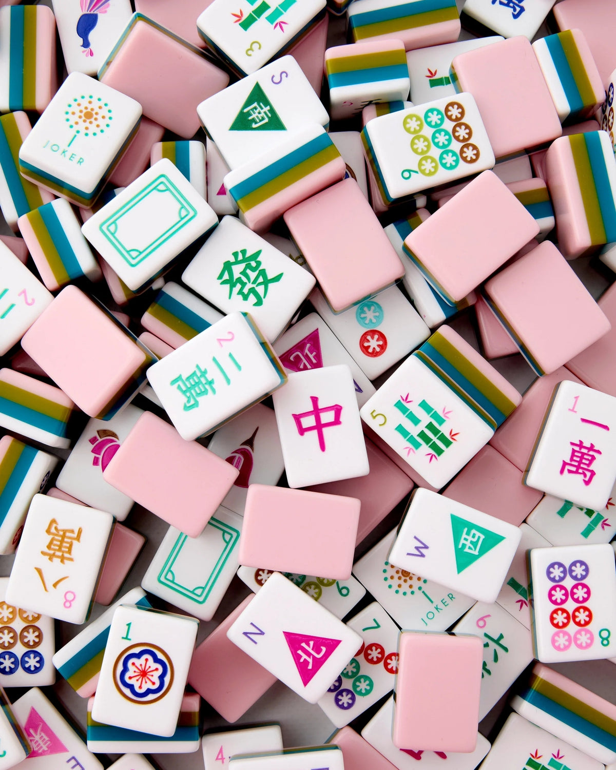 Acrylic mahjong tiles close-up showing white squares with colorful symbols and pink blocks.