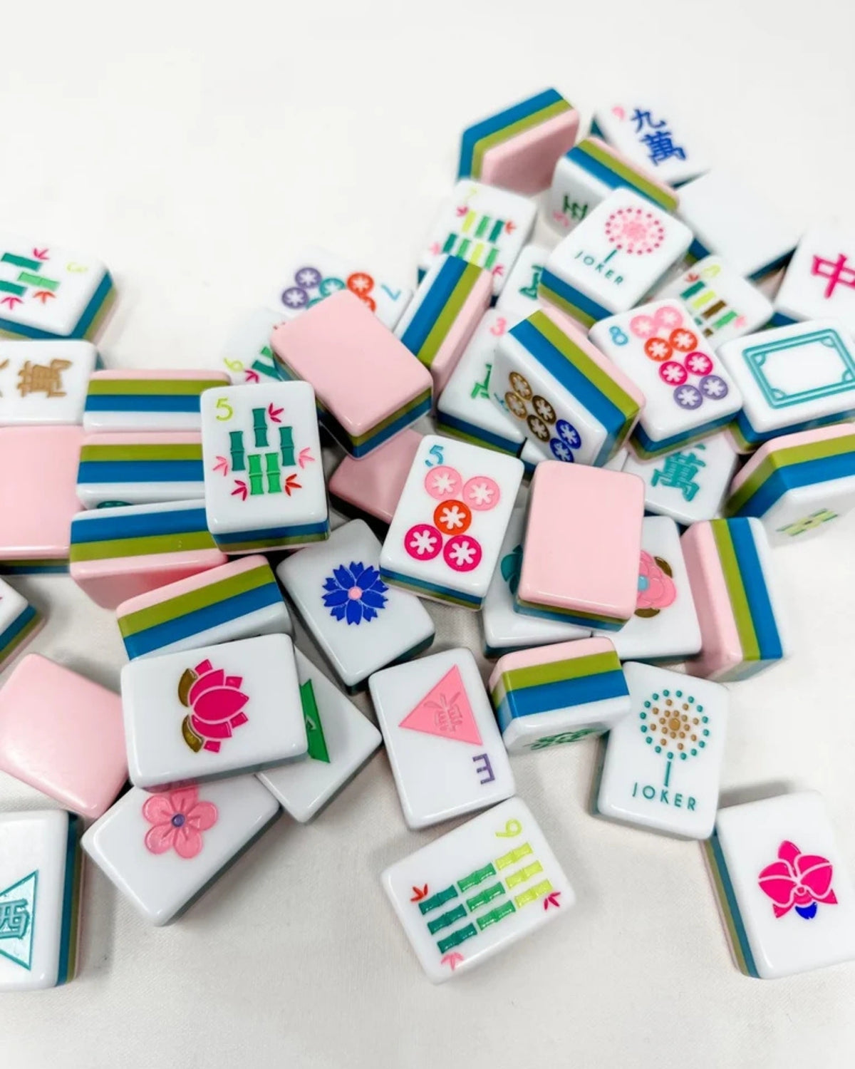 Acrylic mahjong tiles with white faces, colorful characters, and pink tile backs.