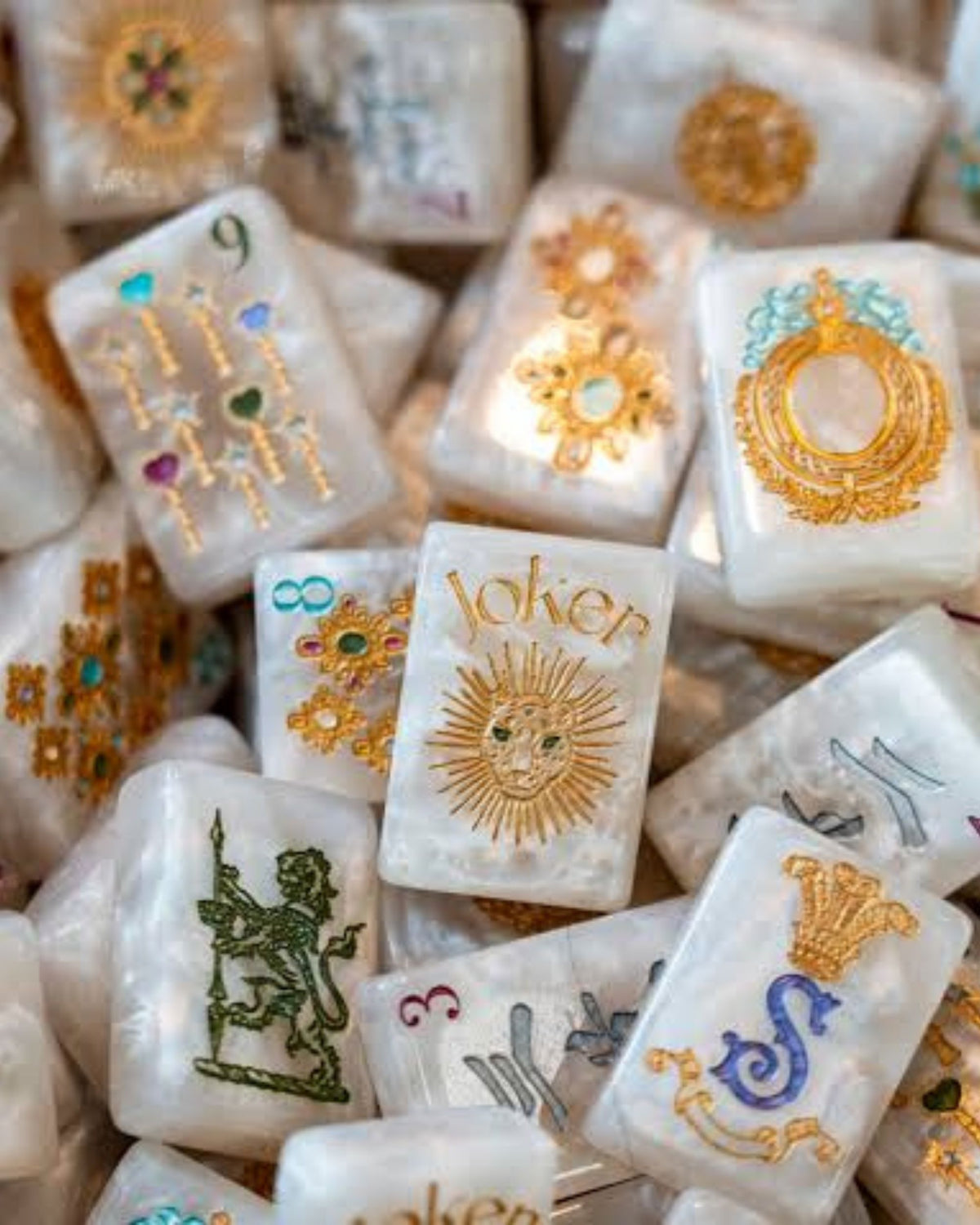 Pearlescent mahjong tiles in a pile, with Joker tile and ornate gold and jewel accents