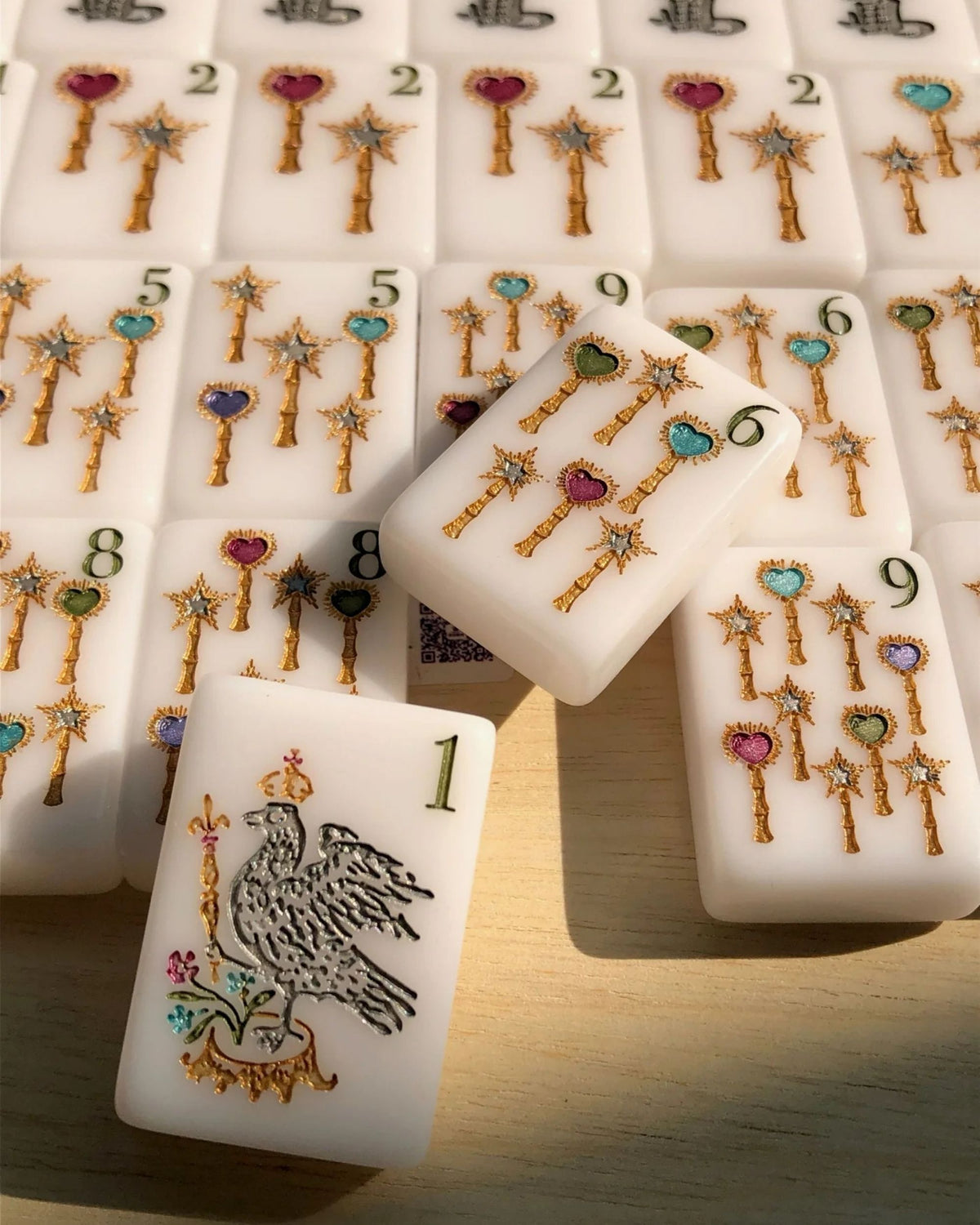 Pearlescent mahjong tiles showing numbered faces and gold filigree key-like symbols