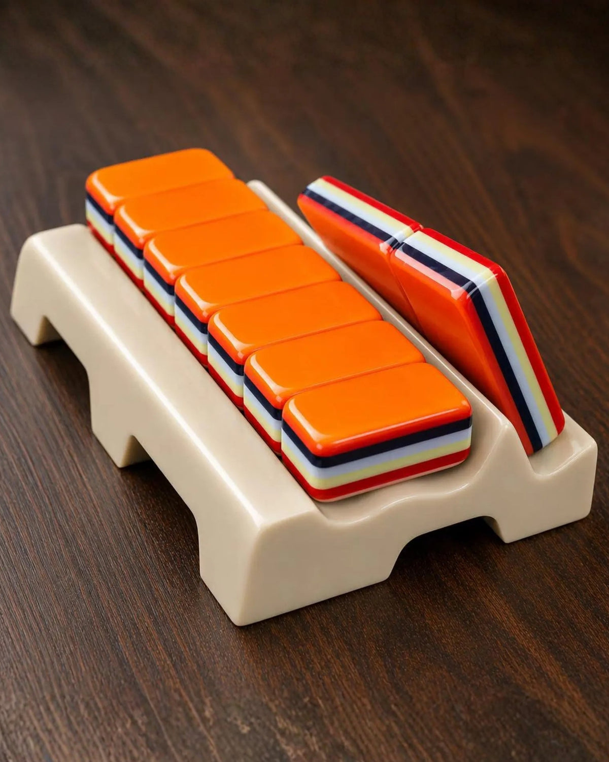 Stacked orange mahjong tiles with striped sides on a cream plastic rack