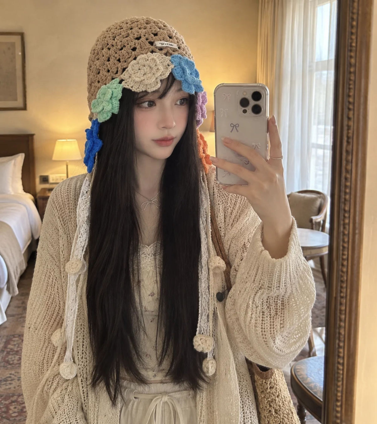 Crochet bonnet in tan with multicolor flower accents and pom pom lace tie ends
