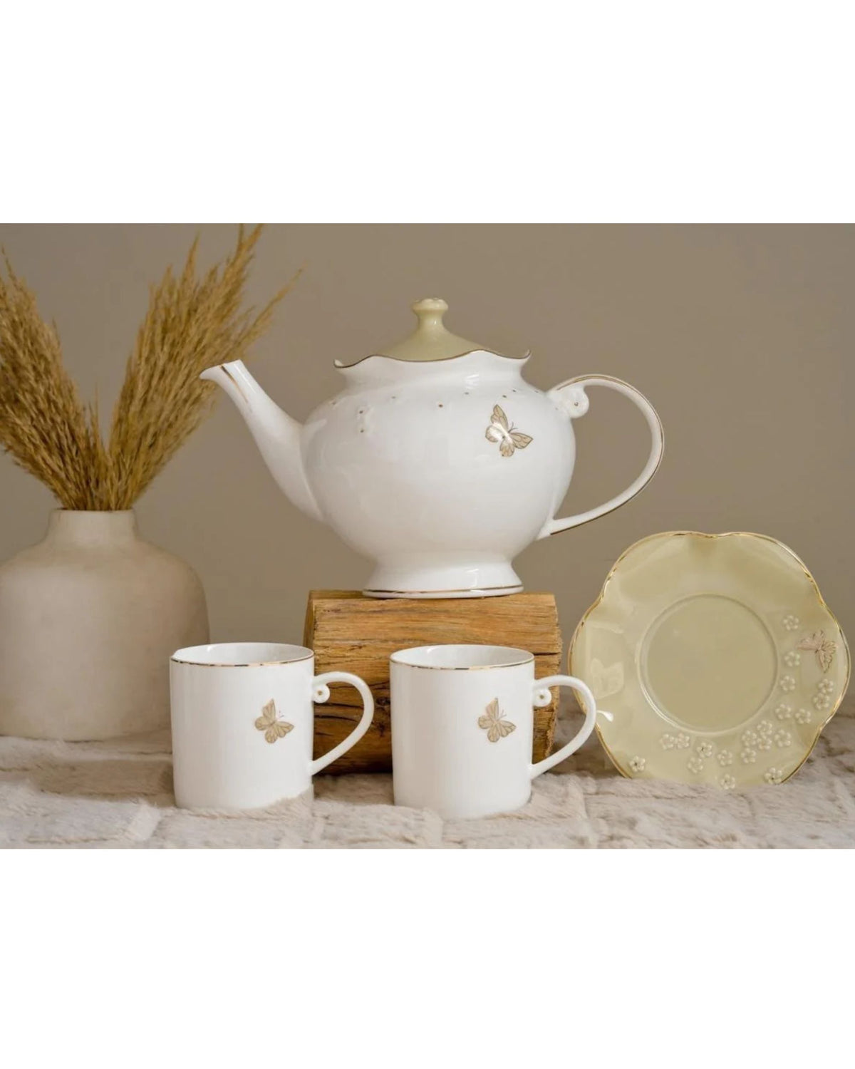 White butterfly coffee mugs and saucer beside a matching teapot