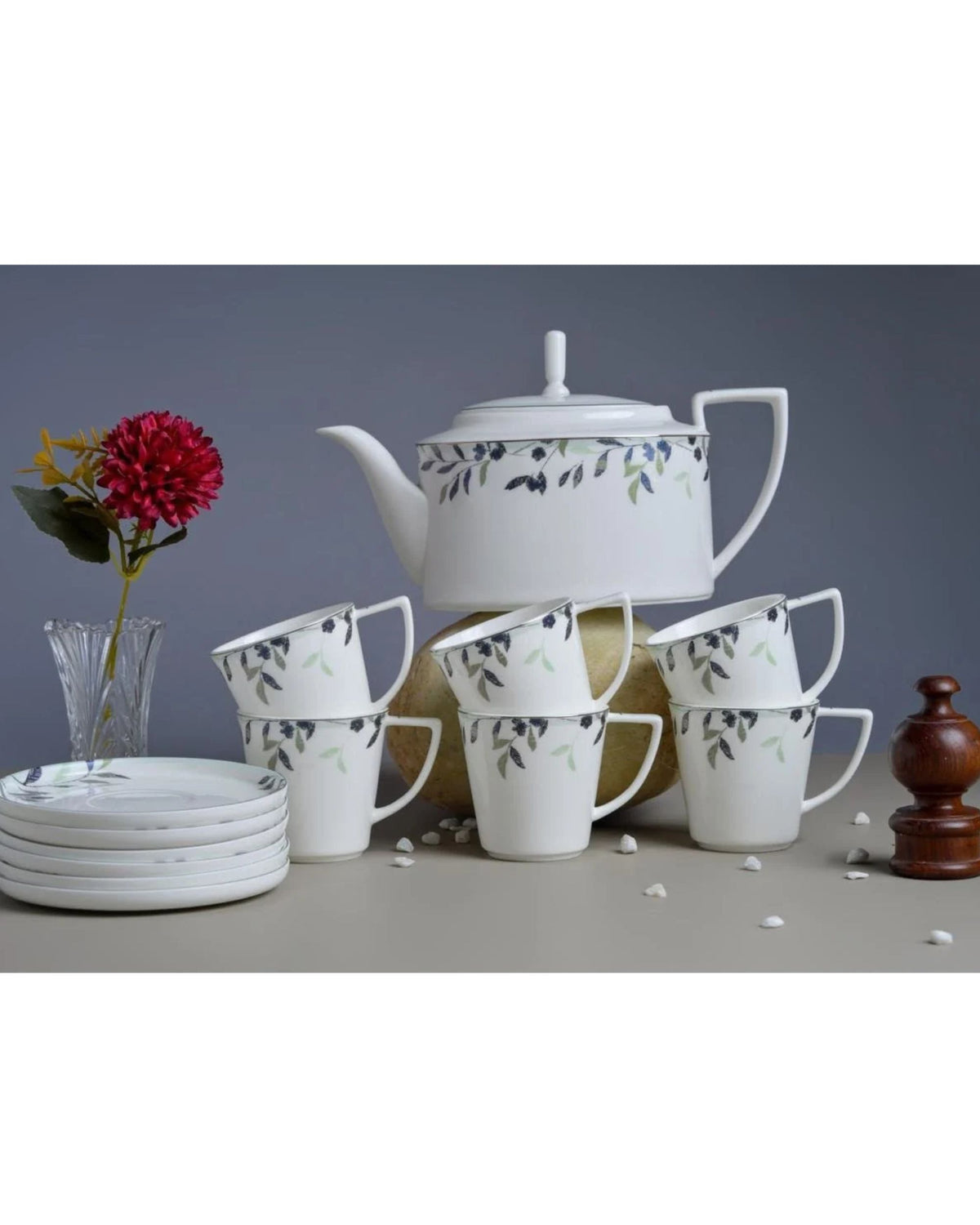 White floral print coffee mugs arranged with a matching teapot and saucers.